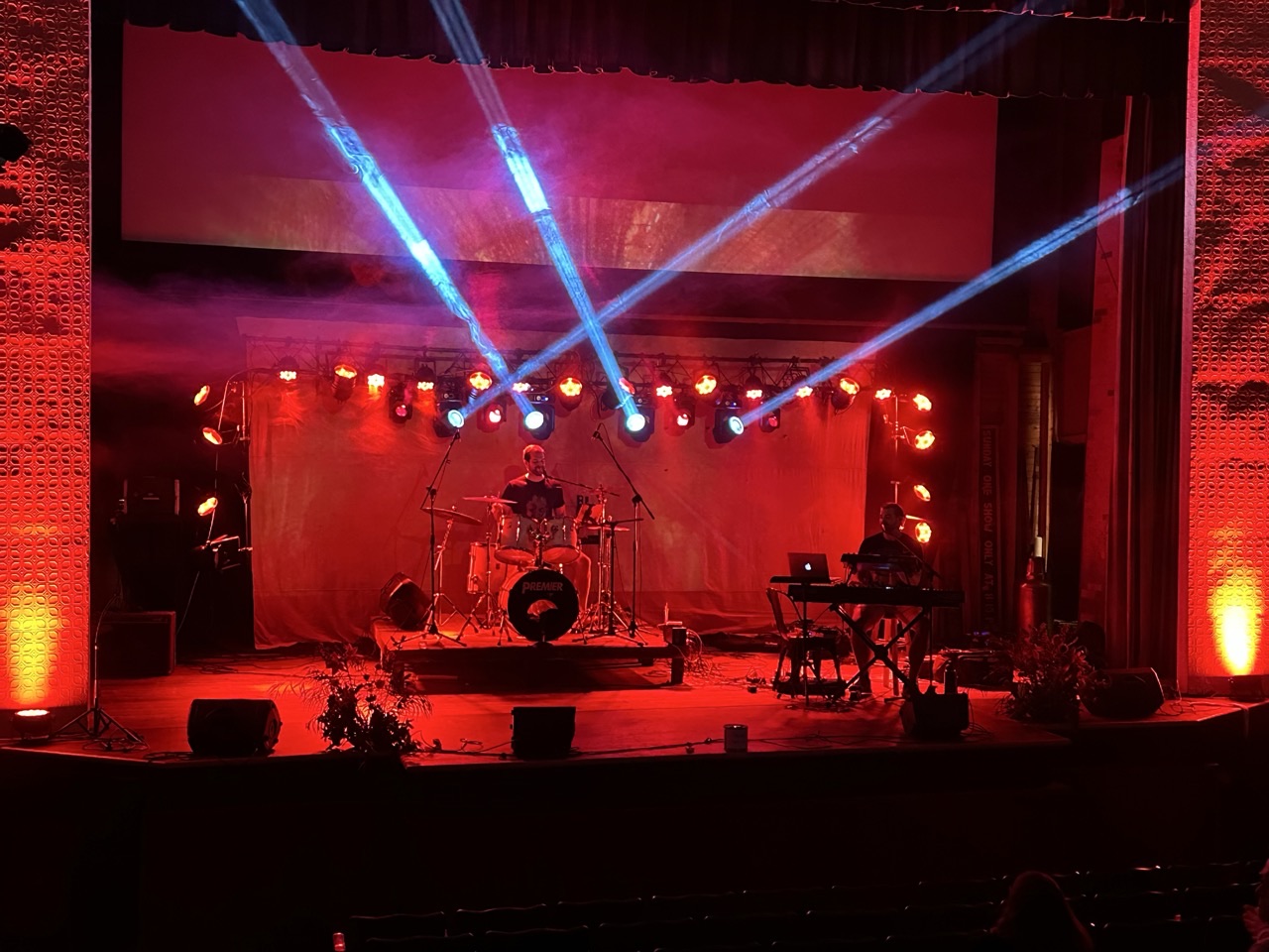 Hot Popsicle performing on a theater stage under red and blue stage lighting
